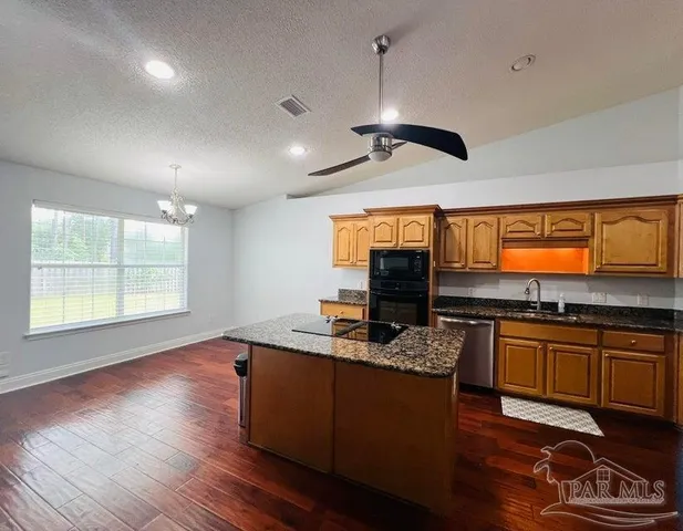 a kitchen with stainless steel appliances granite countertop a stove and a wooden floor
