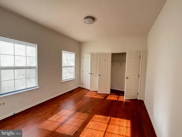 a view of an empty room with window and wooden floor