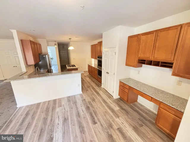 a view of a kitchen with kitchen island a sink wooden floor and a large window