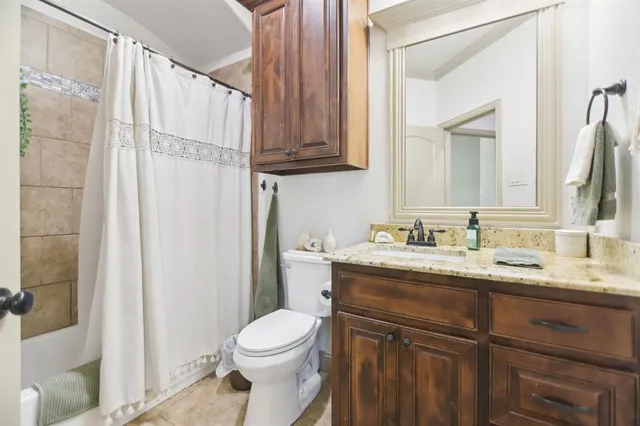 a bathroom with a granite countertop sink mirror vanity and toilet