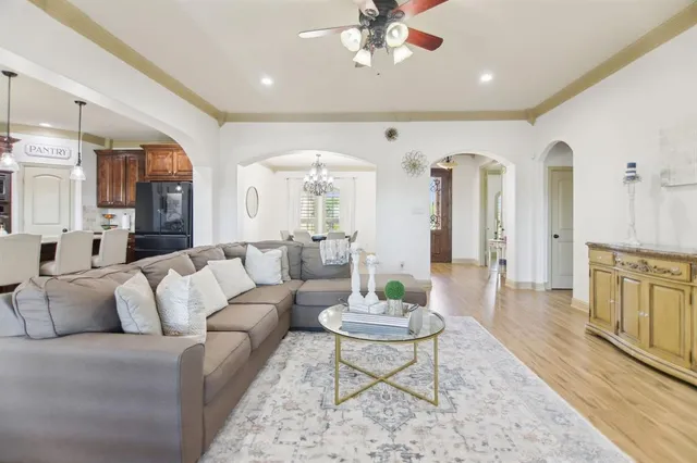 a living room with furniture kitchen view and a chandelier