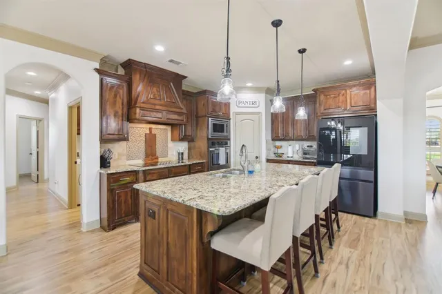 a open kitchen with stainless steel appliances granite countertop a refrigerator a oven a kitchen island a table and chairs