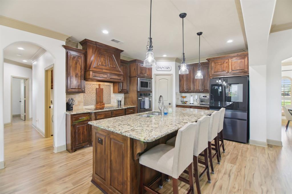 15110 Rutledge Lane Talty, TX 75126 - Photo 10 of 40 a open kitchen with stainless steel appliances granite countertop a refrigerator a oven a kitchen island a table and chairs