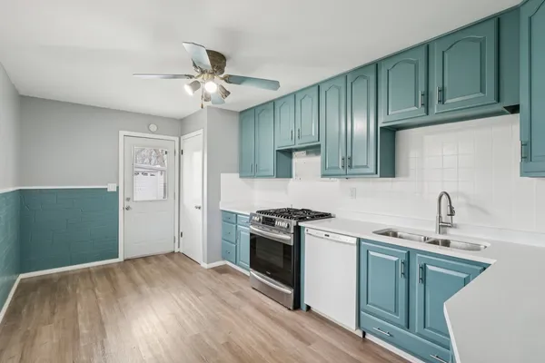 a kitchen with granite countertop a stove a sink and dishwasher with wooden cabinets