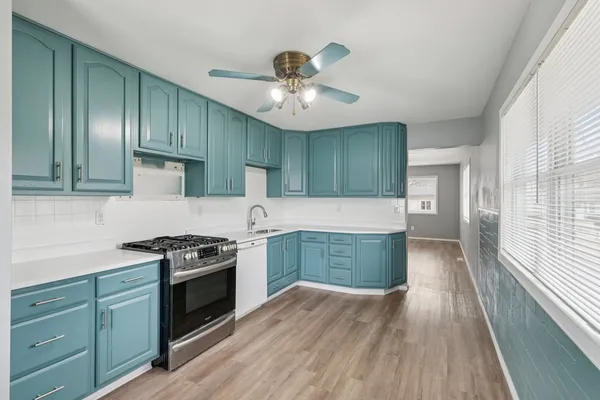 a kitchen with granite countertop a stove a sink and dishwasher with wooden floors