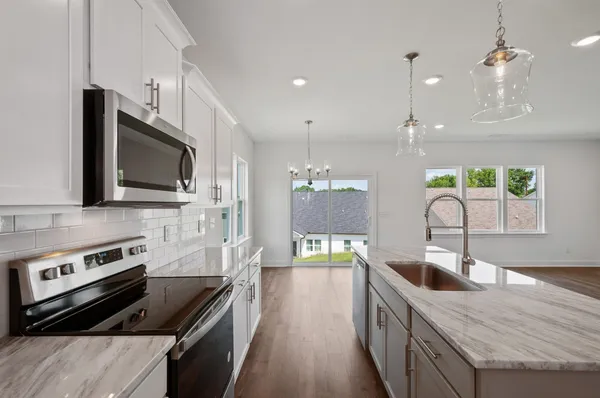 a kitchen with stainless steel appliances granite countertop a sink a stove top oven a counter space and cabinets