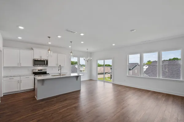 a kitchen with stainless steel appliances kitchen island wooden cabinets and wooden floor