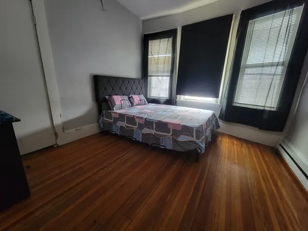 a bedroom with a bed and wooden floor