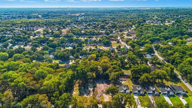 an aerial view of residential houses with outdoor space and trees