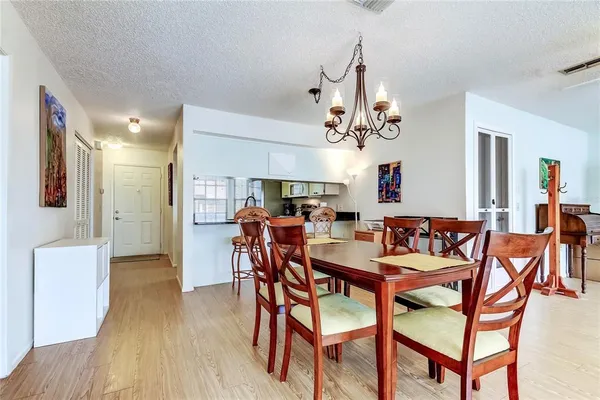 a view of a dining room and livingroom with furniture wooden floor a chandelier