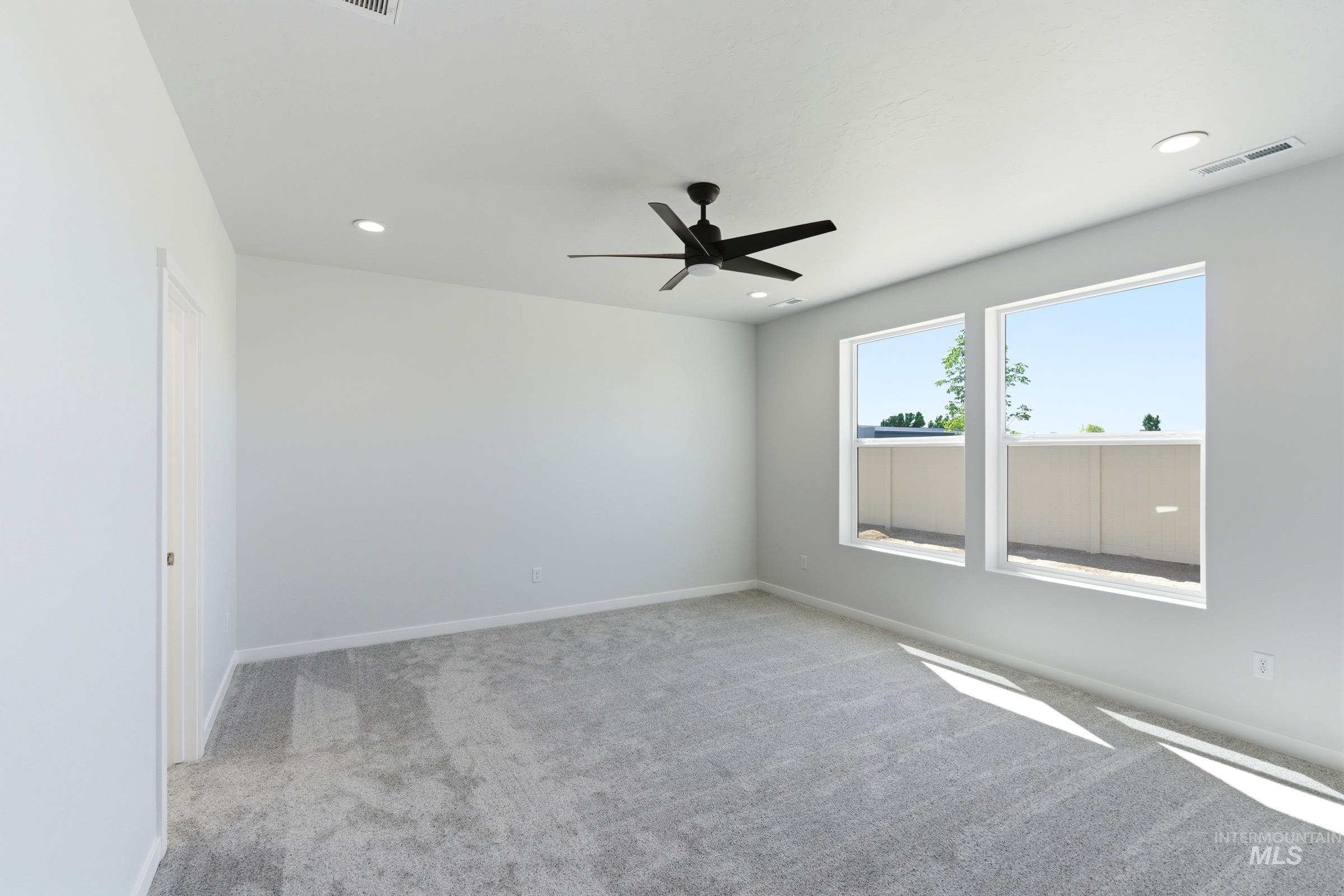 13663 Redway Court Caldwell, ID 83607 - Photo 27 of 32 Spacious room featuring light gray carpeting, a modern ceiling fan with matte black blades, two large windows, recessed lighting, and a white interior door