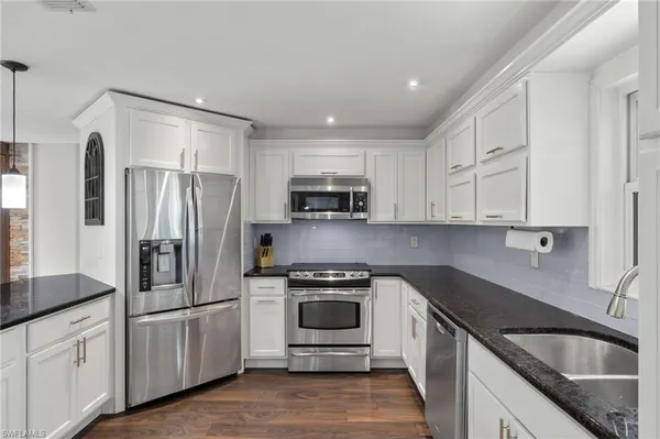 a kitchen with white cabinets and stainless steel appliances