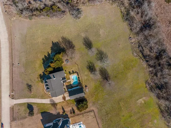 an aerial view of a house with a yard and large trees