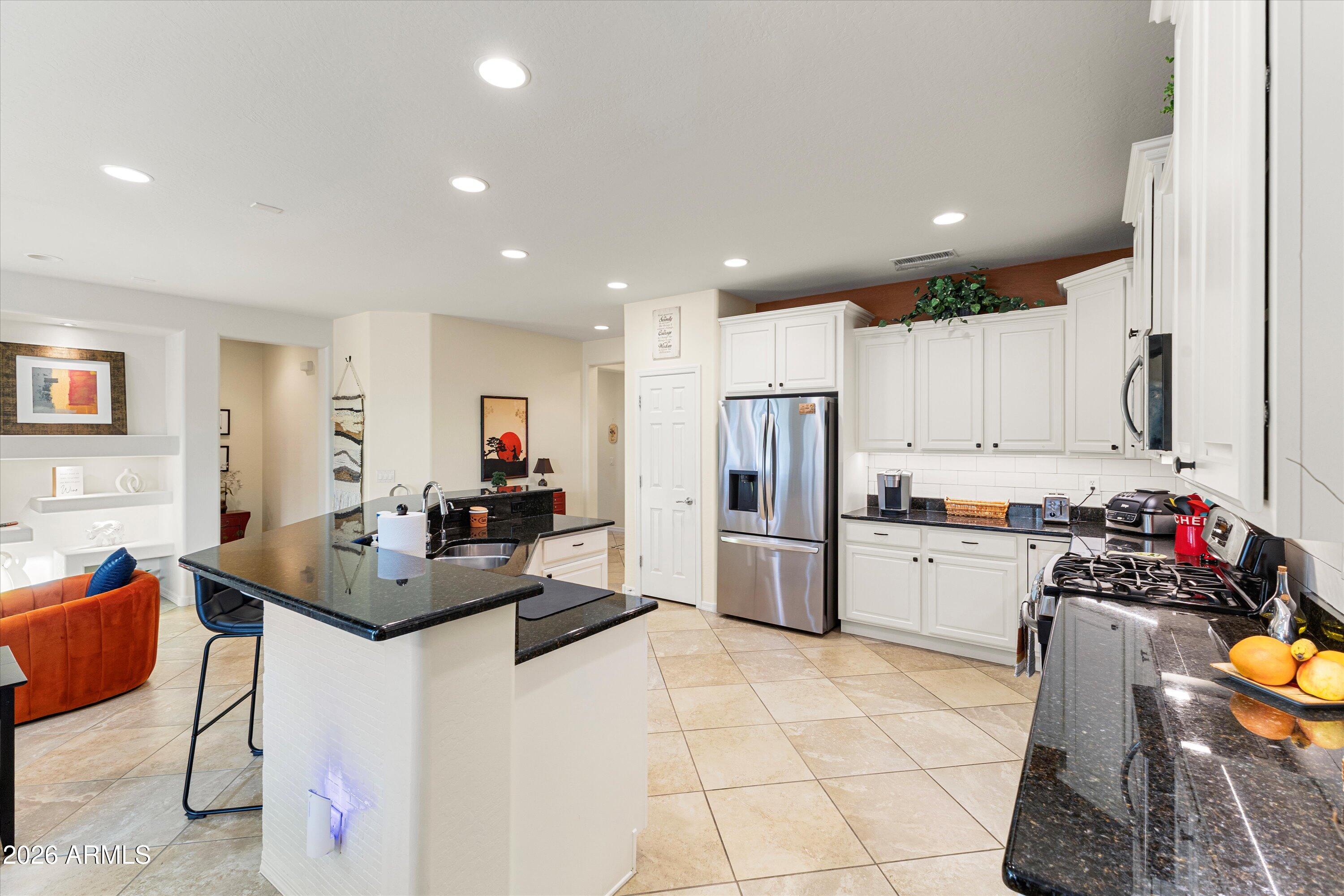 20652 North 267th Avenue Buckeye, AZ 85396 - Photo 17 of 53 a kitchen with stainless steel appliances kitchen island granite countertop a stove a sink a refrigerator and white cabinets with wooden floor