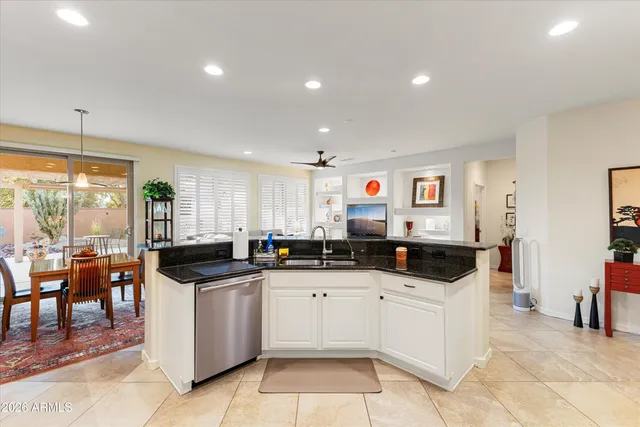 a kitchen with stainless steel appliances kitchen island granite countertop a stove a sink a refrigerator and white cabinets with wooden floor