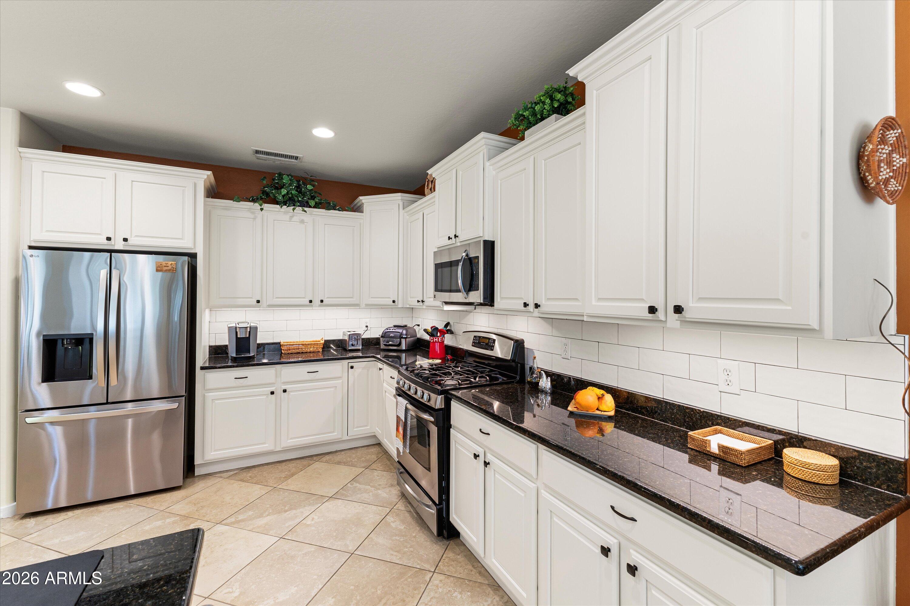 20652 North 267th Avenue Buckeye, AZ 85396 - Photo 20 of 53 a kitchen with stainless steel appliances granite countertop a refrigerator sink and stove