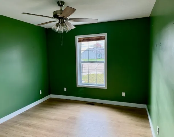 a view of an empty room with a window and a ceiling fan