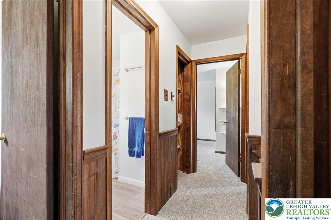 1385 Woodmere Road Pottstown, PA 19464 - Photo 35 of 57 A well-lit hallway with natural wood trim leading to multiple rooms, showcasing plush carpeting and classic design elements.