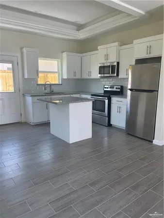 a kitchen with stainless steel appliances granite countertop a refrigerator a stove top oven a sink and dishwasher with wooden floor