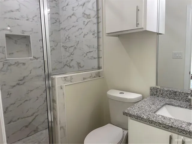 a bathroom with a granite countertop toilet and a sink