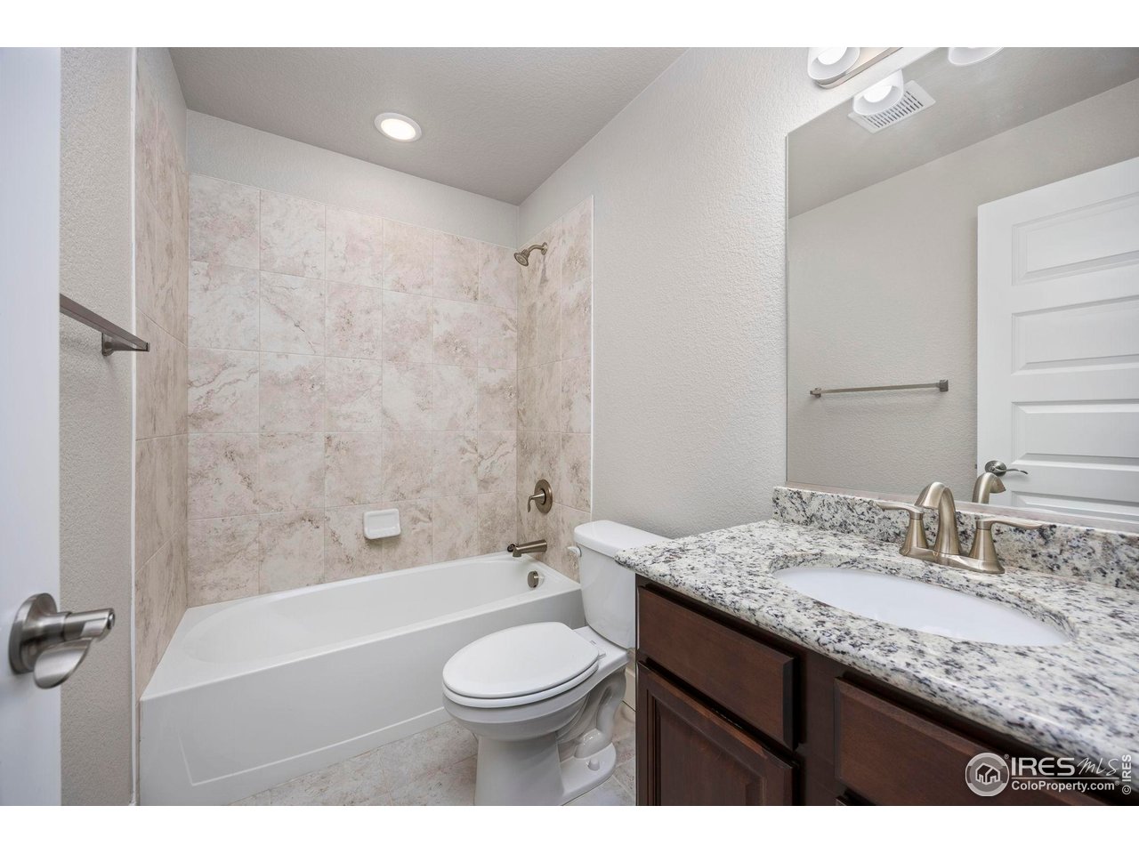 1344 87th Avenue Greeley, CO 80634 - Photo 23 of 31 a bathroom with a granite countertop sink a toilet a mirror and bathtub