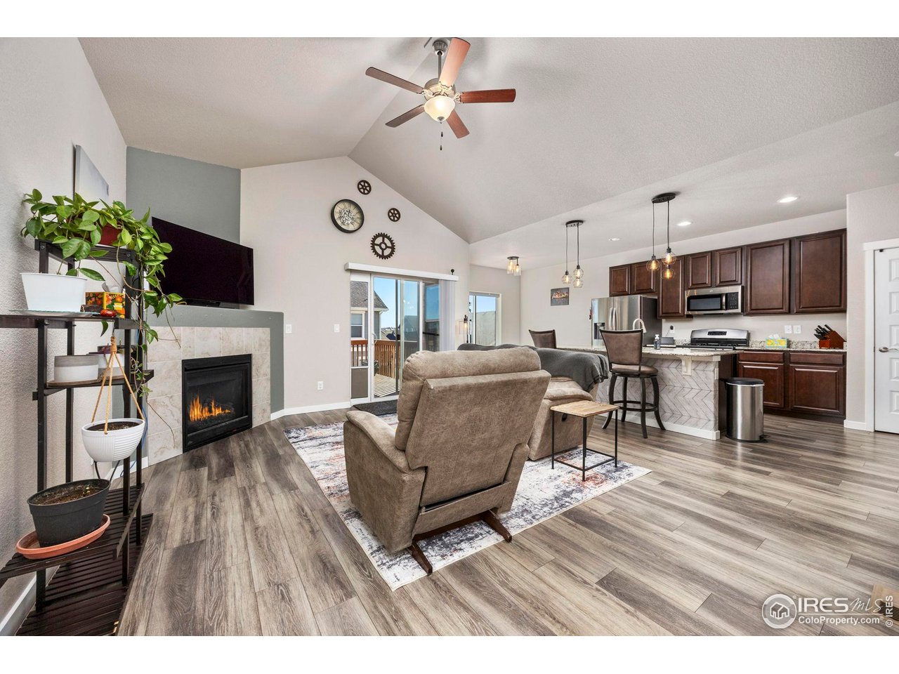 1344 87th Avenue Greeley, CO 80634 - Photo 5 of 31 a living room with furniture a fireplace and a flat screen tv