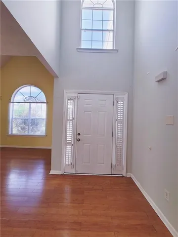 an empty room with wooden floor cabinet and windows
