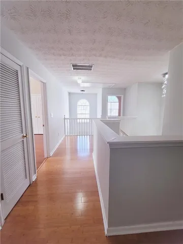 a view of a hallway with wooden floor and staircase