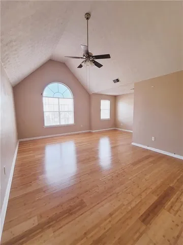 an empty room with wooden floor chandelier and windows