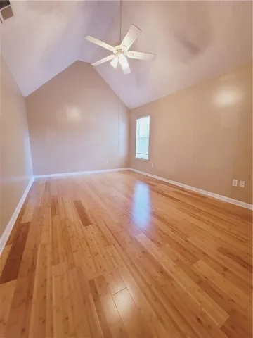 an empty room with wooden floor fan and windows