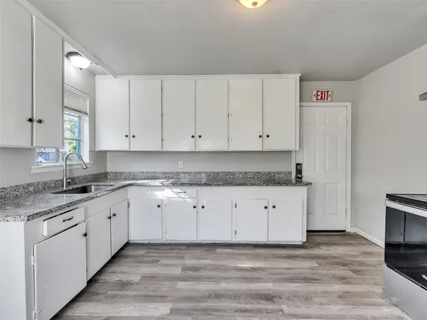 a kitchen with granite countertop white cabinets white stainless steel appliances and a sink