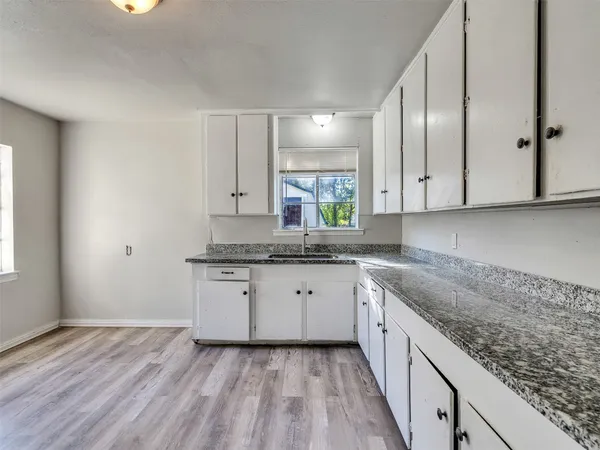 a kitchen with granite countertop cabinets stainless steel appliances a sink and wooden floor