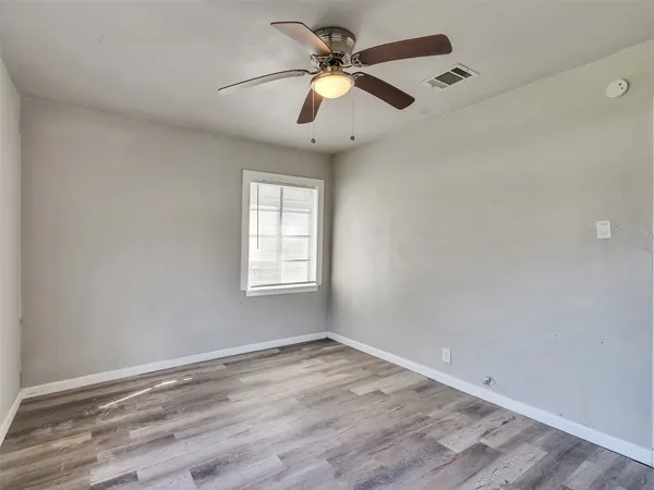 an empty room with a window and a fan