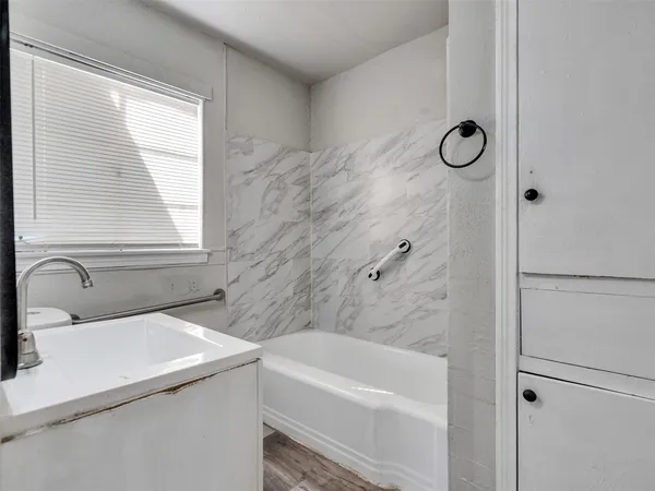 a bathroom with a tub sink a window and a shower