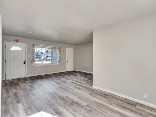 an empty room with wooden floor cabinet and windows