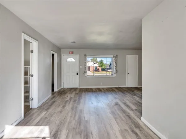 an empty room with wooden floor mirror and windows
