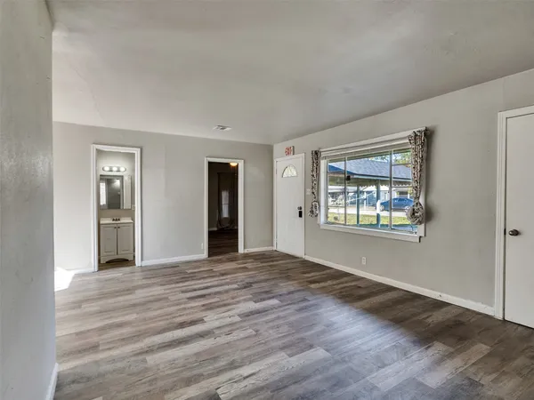 a view of an empty room with window and wooden floor