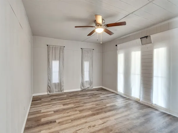 a view of an empty room with window and chandelier fan