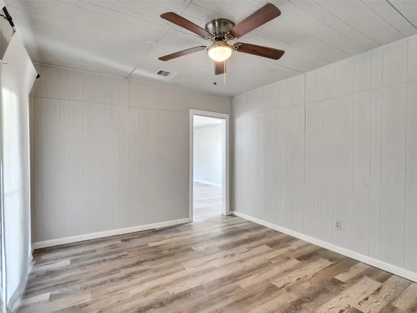 an empty room with wooden floor and ceiling fan