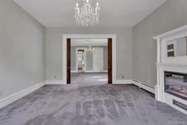 a view of a livingroom with a fireplace a chandelier and windows