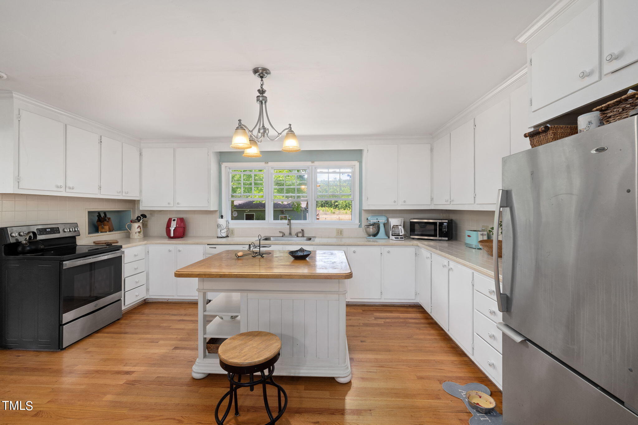 212 Hawkins Road Cedar Grove, NC 27231 - Photo 7 of 36 a kitchen with stainless steel appliances a sink a stove a refrigerator cabinets and wooden floor