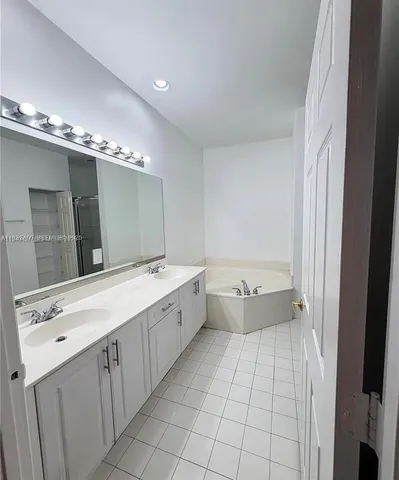 a bathroom with a granite countertop sink a large mirror and a bathtub