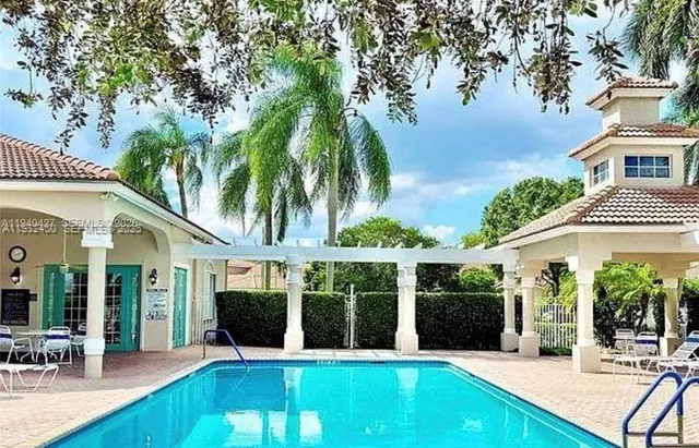 a view of a white house with a large pool table and chairs