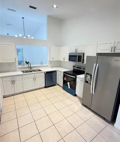 a kitchen with stainless steel appliances a sink a stove a microwave a center island and cabinets