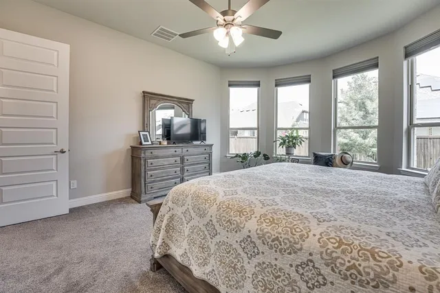 a spacious bedroom with a bed and flat screen tv