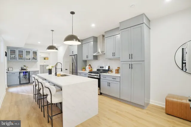 a kitchen with stainless steel appliances kitchen island granite countertop a stove a sink dishwasher and white cabinets with wooden floor