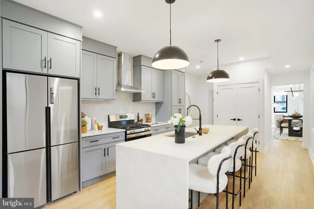 a kitchen with stainless steel appliances a refrigerator a sink a stove a table and chairs