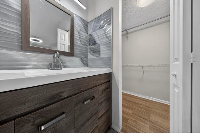 a bathroom with a granite countertop sink a mirror and a shower