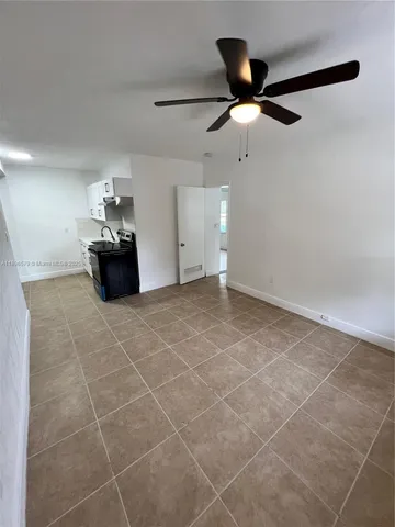 a living room with stainless steel appliances furniture and a ceiling fan