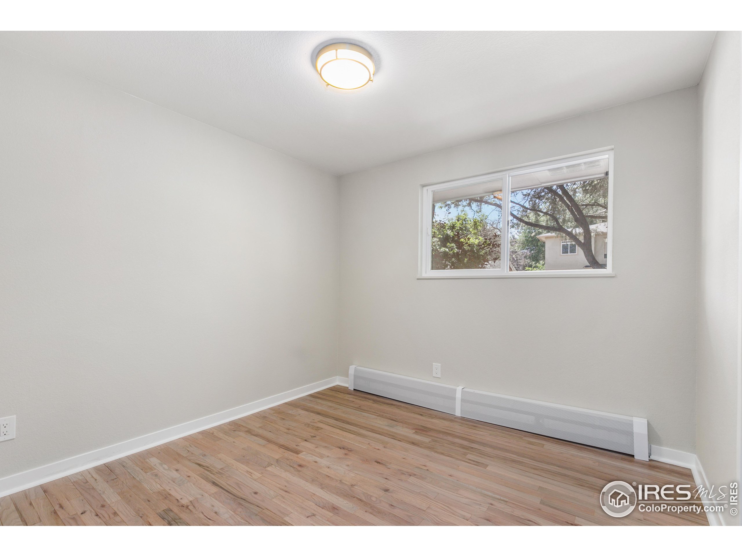 1120 Hartford Drive Boulder, CO 80305 - Photo 16 of 40 an empty room with wooden floor and painting on the wall
